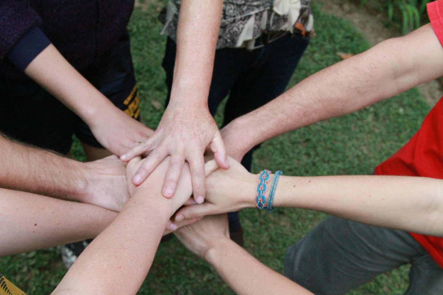 Diverse hands stacked together symbolizing teamwork and unity.